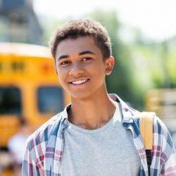 Aws Teenage African American Student In Front Of School Bus