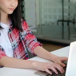 Girl In Plaid Shirt Typing On Laptop
