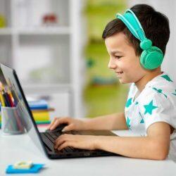 Young Boy With Headphones On While Using Laptop